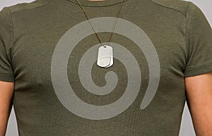 A soldier in a T-shirt with a military name medallion around his neck. Strong physique of a military pensioner.