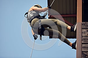 Soldier training rappel with rope. Military woman does hanging on climbing equipment