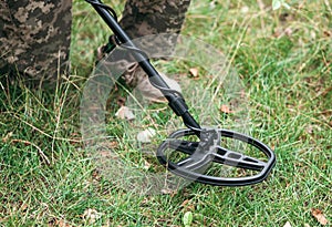 Soldier using a metal detector in fields. Ukrainian Explosive Ordnance Disposal Officer detecting metal by metal detector device