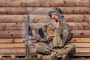 Soldier using tablet computer against old wooden wall in military camp to stay in contact with friends and family