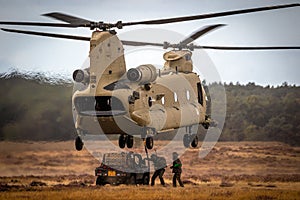 Soldiers attatching a military all-terrain vehicle to a Boeing CH-47F Chinook helicopter. Ginkelse Heide, The Netherlands -
