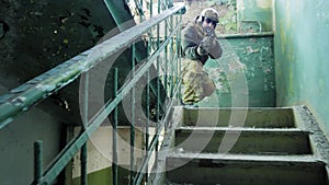 Soldiers in camouflage with combat weapons sneak along the corridors of the old building, the military concept