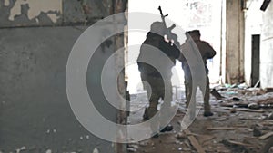 Soldiers in camouflage with combat weapons sneak along the corridors of the old building, the military concept