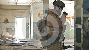 Soldiers in camouflage with combat weapons sneak along the corridors of the old building, the military concept