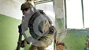 Soldiers in camouflage with combat weapons sneak along the corridors of the old building, the military concept