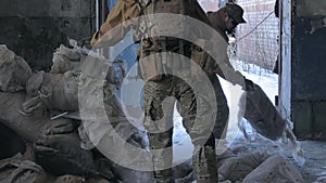 Soldiers in camouflage with combat weapons sneak along the corridors of the old building, the military concept