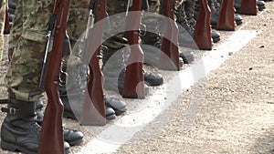 Soldiers in camouflage uniform standing at attention with guns at their feet.