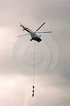 Soldiers go down a rope from military helicopter