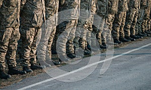 Soldiers legs in military uniform and boots standing in line at camp