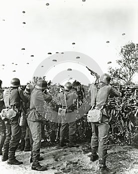 Soldiers shooting at enemy parachuting into field photo
