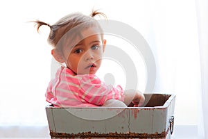 Solemn baby girl in wooden box