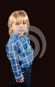 Solemn little boy against a dark background