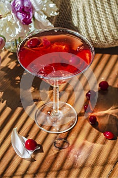 Solemn rustic still life with glass of red drink with autumn berries and white flowers on wooden table and textile in striped