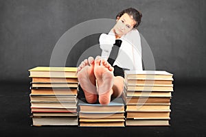 Soles of bare feet of teenage girl on top of old books