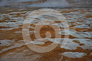 Solfatare mudpot s in the geothermal area Hverir, Iceland. The area around the boiling mud is multicolored and cracked