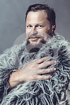 Solid bearded man in a fur mantle studio portrait