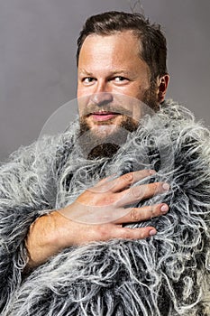 Solid bearded man in a fur mantle studio portrait