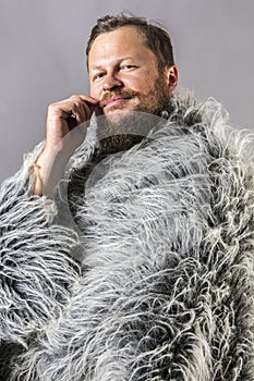 Solid bearded man in a fur mantle studio portrait