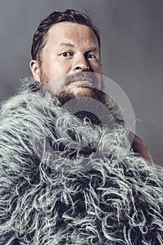 Solid bearded man in a fur mantle studio portrait