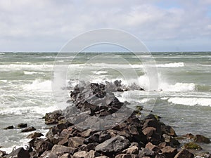 Solid breakwater rocks with cloudy ocean horizon