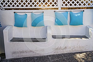 Solid built-in white concrete custom design bench seat chair with light blue pillow hanging by steel rod along island walkway
