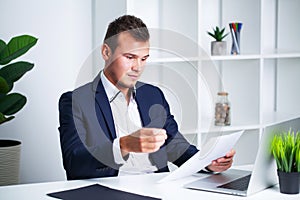 Solid businessman in a jacket works with documents in office of the company.