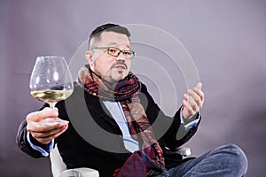 Solid cheerful man in kerchief sitting with glass of wine