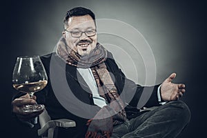 Solid cheerful man in kerchief sitting with glass of wine