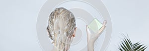 Solid hair shampoo. Close-up of a blonde girl in the bathroom, which lathers her hair with dry shampoo. Lots of foam and peek