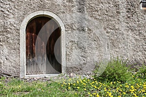 A solid historic stone wall with a wooden closed door