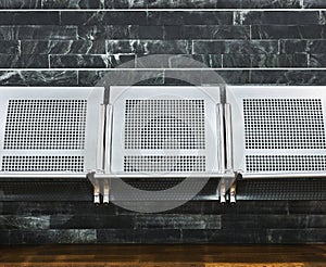 Solid metal benches on a tiled wall and a wooden floor photo