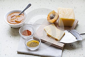 Solid sliced cheese with apricot curry in ceramic ware, spices and fresh apricots