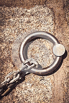 Solid steel ring and mooring lines in a seaport. Rusty iron chain on the ground