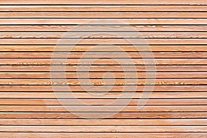 A solid wall of brown wooden planks arranged horizontally. Concept for texture, background, interior