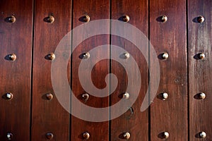 A solid wooden door close-up with rows of metal studs