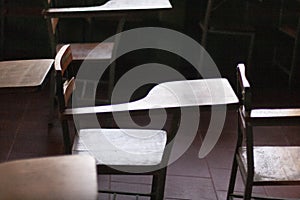 Solitary desks with no students in empty classroom in the dark Caracas Venezuela