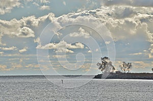 Solitary figure dwarfed by lake and cloud