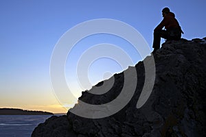 Solitary Figure on Rock overlooking Sunset on Frozen Lake