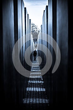 Solitary figure strides through an ancient stone colonnade in Berlin, Germany.