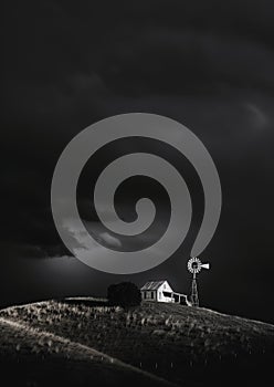 A solitary house stands next to a windmill on a moody evening, illuminated in the twilight