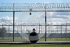 solitary inmate during yard time with fence backdrop