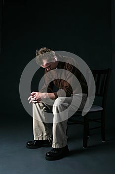 Solitary man sitting on chair with head down