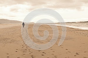 Solitary man taken from behind walking in an empty beach. photo