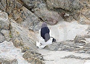 Solitary nun in prayer dressed in a monastic habit and a veil on her head
