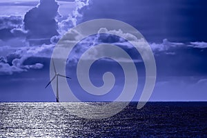 Solitary offshore wind farm turbine by moonlight. Blue toned energy image