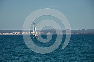 A solitary sailboat sails through the waters of the bay of Palma