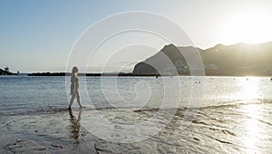 Solitary Teenager walking in the sand of a beach in the sunset having pleasure, relaxing and breathing. Adolescent search or seek