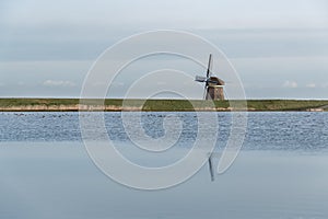 Solitary Thatched Roof Mill on a Green Dike Beside a flooded meadow and Dutch Lake at Dusk