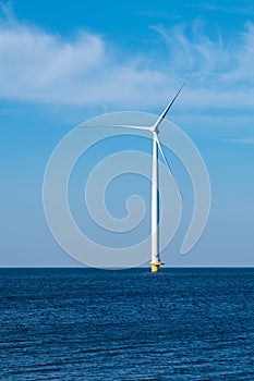 A solitary wind turbine stands tall in the vast ocean, harnessing the power of the wind to generate clean energy for a photo