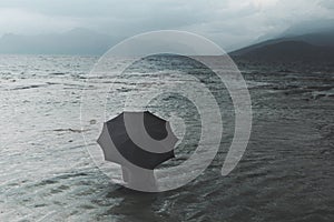 Solitary woman with umbrella waiting for rain sitting in the sea